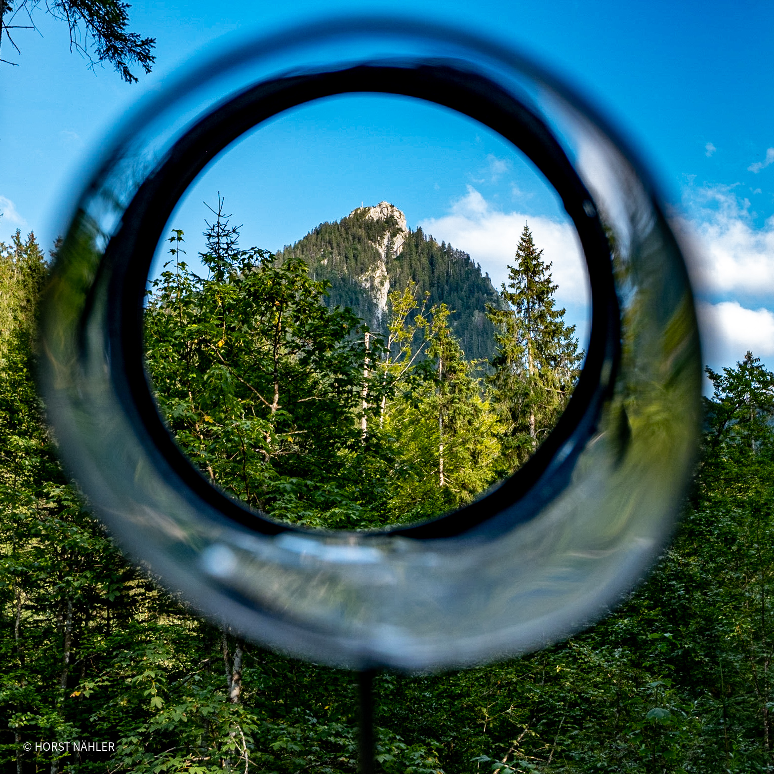 Blick durch Glasring auf Berggipfel im Wald