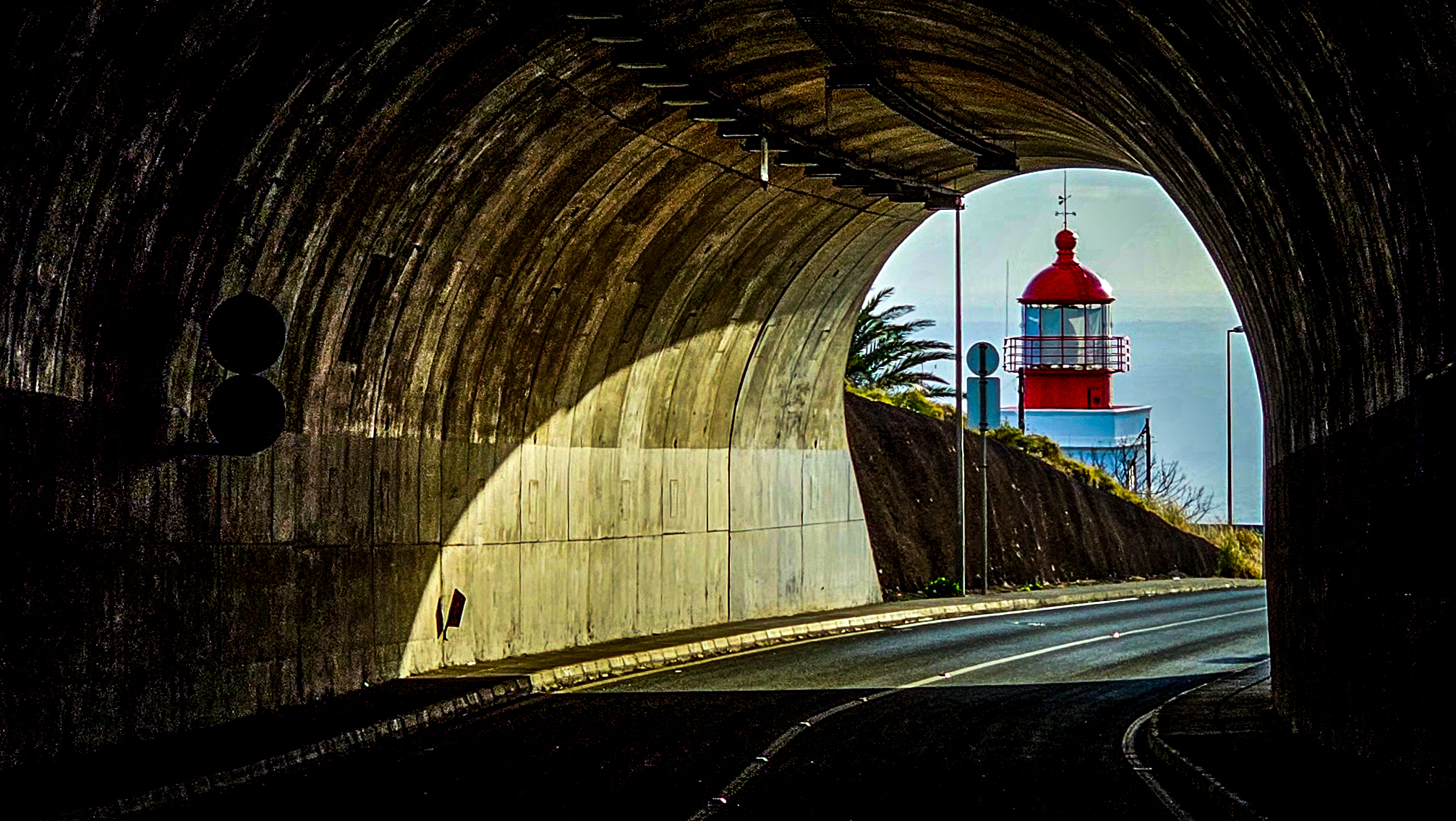 Blick durch Tunnel auf Leuchtturm am Horizont