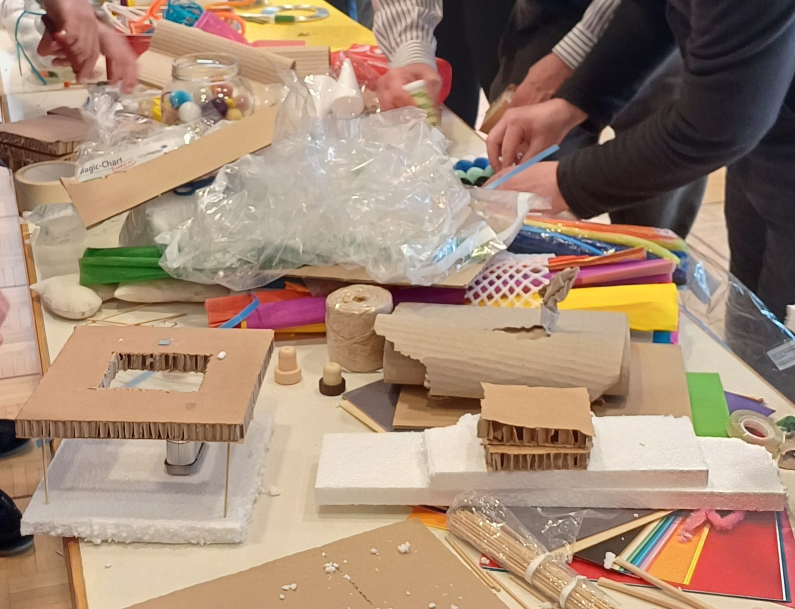 Hände beim Bauen eines Prototyps aus Papier und Alltagsmaterial am Workshop-Tisch