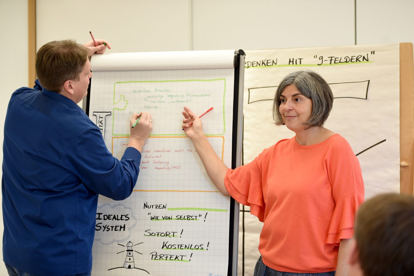 Barbara Gronauer erklärt am Flipchart, Teilnehmende schauen zu