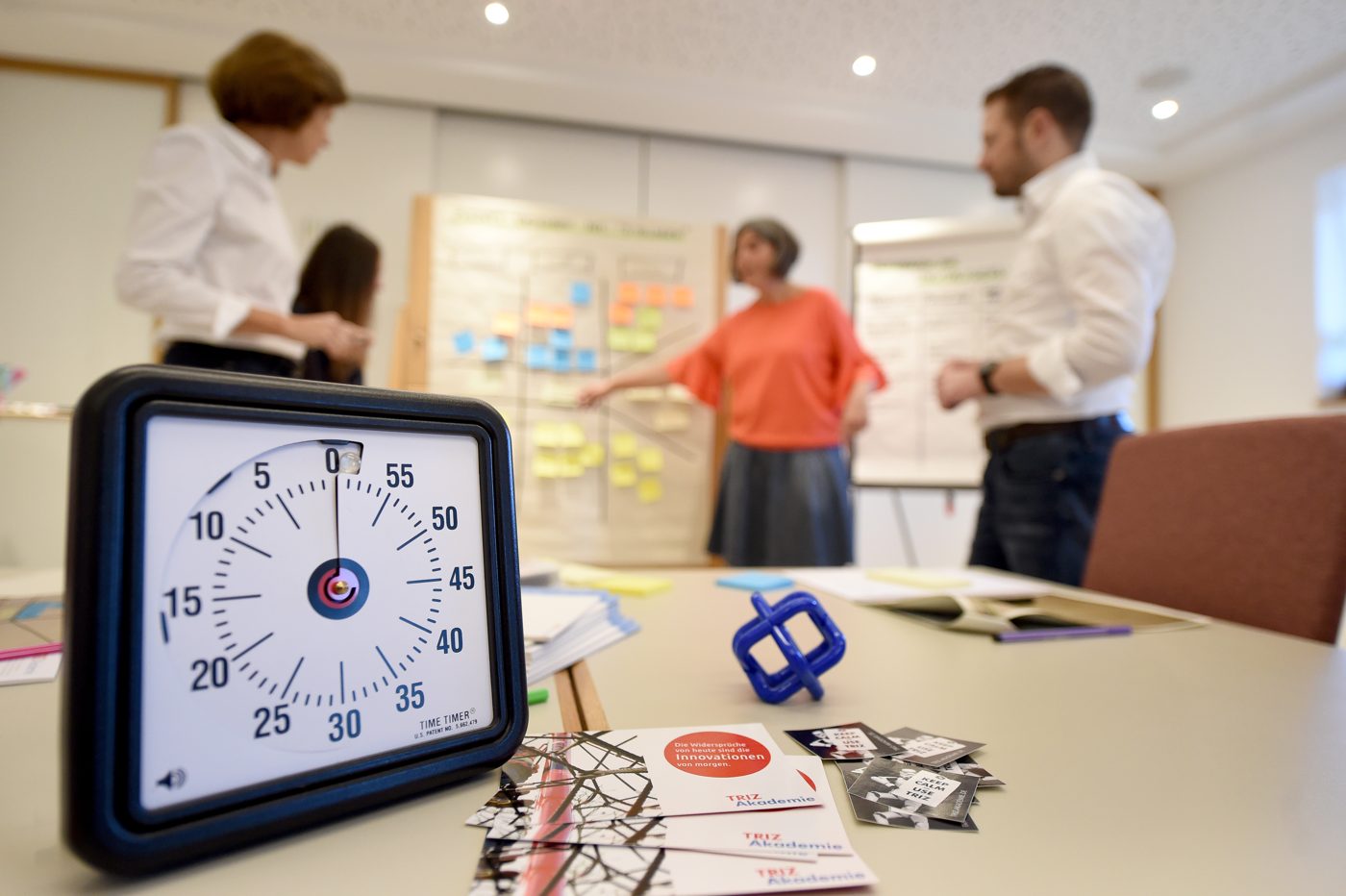 Workshopraum mit Zeitgeber und Gruppenarbeit im Hintergrund